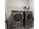 Modern laundry room with grey front-load washer and dryer and upper wire shelf at 2124 Bullock Bluff Dr, Loganville, GA 30052