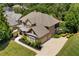 Aerial view of a brick house with a three car garage, mature trees, and a large yard at 307 Heritage Overlook, Woodstock, GA 30188