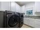 Modern laundry room with front loading washer and dryer and white cabinets at 1020 Matheson Way, Johns Creek, GA 30022