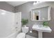 Well-lit bathroom featuring a shower-tub combination, pedestal sink, decorative mirror and neutral gray walls at 672 Red Sunset Cir, Powder Springs, GA 30127
