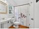 Bright bathroom with white fixtures, hardwood floors, and a shower with a decorative curtain at 672 Red Sunset Cir, Powder Springs, GA 30127