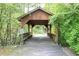 Charming covered wooden bridge with seating, nestled amongst trees, providing a unique and inviting walkway at 672 Red Sunset Cir, Powder Springs, GA 30127