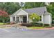 Exterior view of the community clubhouse featuring a covered entrance, lush landscaping, and ample parking at 672 Red Sunset Cir, Powder Springs, GA 30127