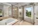 Bathroom with a walk-in shower, soaking tub, tiled walls, and a window providing natural light at 11271 Calypso Dr, Alpharetta, GA 30009