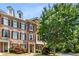 A stately brick townhome displays an inviting entrance with a blooming tree, offering curb appeal at 11271 Calypso Dr, Alpharetta, GA 30009