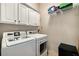 Functional laundry room with a washer, dryer, white cabinets, and overhead shelving at 11271 Calypso Dr, Alpharetta, GA 30009
