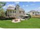 A well-manicured backyard with a stone firepit and patio area, adjacent to a lovely house with a sunroom at 558 Grand Ivey Pl, Dacula, GA 30019