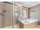 Bathroom featuring glass shower, soaking tub, and a stained glass window at 558 Grand Ivey Pl, Dacula, GA 30019