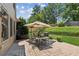 Relaxing brick patio featuring an outdoor dining set, grill, and professionally landscaped backyard at 558 Grand Ivey Pl, Dacula, GA 30019