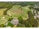 Picturesque aerial view of a golf course with a serene pond, surrounded by lush trees and a community clubhouse at 7048 Bennington Ln, Cumming, GA 30041