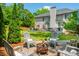 Backyard featuring a stone patio with firepit, patio furniture, a large grassy lawn, and mature trees at 7048 Bennington Ln, Cumming, GA 30041