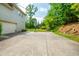 Large concrete parking pad and driveway with a basketball hoop and green foliage in the background at 7048 Bennington Ln, Cumming, GA 30041