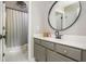 Bathroom featuring gray cabinetry, a circular mirror, and neutral finishes at 7048 Bennington Ln, Cumming, GA 30041