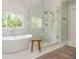 Modern bathroom showcasing a soaking tub, glass-enclosed shower, and tiled walls at 7048 Bennington Ln, Cumming, GA 30041