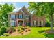 Elegant brick home featuring manicured landscaping and a lush green lawn at 7048 Bennington Ln, Cumming, GA 30041