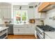 Bright kitchen features white cabinets, subway tile backsplash, and a farmhouse sink at 7048 Bennington Ln, Cumming, GA 30041