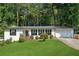 Charming single-story home with a well-manicured lawn, mature trees, and an attached garage at 5360 Fieldgreen Dr, Stone Mountain, GA 30088