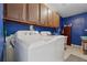 Laundry room with newer washer and dryer, upper cabinets, and blue walls at 5360 Fieldgreen Dr, Stone Mountain, GA 30088