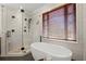 Close up of a glass enclosed shower, soaking tub, and marble tile backsplash in this spacious bathroom at 6325 Haddington Ln, Suwanee, GA 30024
