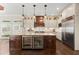 Modern kitchen with stainless steel appliances, large island with wine cooler, and custom cabinetry at 6325 Haddington Ln, Suwanee, GA 30024