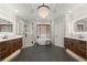 A luxurious bathroom featuring dual vanities, a freestanding tub, glass enclosed shower, and a modern chandelier at 6325 Haddington Ln, Suwanee, GA 30024