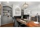 Beautiful home office with custom built-ins, dark wood desk, elegant lighting and an arched mirror over the fireplace at 6325 Haddington Ln, Suwanee, GA 30024