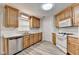 Well-lit kitchen featuring wood cabinets, white appliances, and wood-look flooring at 430 Tara Oaks Ct, Lawrenceville, GA 30043