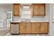 Traditional kitchen featuring wood cabinets, laminate countertops, stainless steel dishwasher, and view to the backyard at 430 Tara Oaks Ct, Lawrenceville, GA 30043