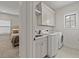 Bright laundry room featuring modern washer and dryer, with a convenient sink and ample white cabinet storage at 630 Brashy St, Woodstock, GA 30188