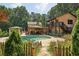 Lush backyard featuring a sparkling pool, covered seating area, and mature trees, perfect for entertaining at 1024 Lake Charles Dr, Roswell, GA 30075