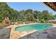 Beautiful swimming pool and outdoor space featuring a stone patio, lounge chairs, mature trees, and meticulous landscaping at 1024 Lake Charles Dr, Roswell, GA 30075