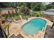 Gorgeous pool area with stone surround, fireplace, chaise lounges, and landscaped green space, perfect for relaxation and entertaining at 1024 Lake Charles Dr, Roswell, GA 30075