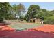 Full-sized tennis court and play area with green and red court surfaces surrounded by mature trees and lush landscaping at 1024 Lake Charles Dr, Roswell, GA 30075