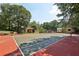 Full-sized tennis court and play area with green and red court surfaces surrounded by mature trees and lush landscaping at 1024 Lake Charles Dr, Roswell, GA 30075