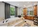 A luxurious bathroom featuring a soaking tub, large window, and wooden vanity with dual sinks at 105 Postwood Dr, Fayetteville, GA 30215