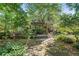 Lush backyard with a stone path, deck, and mature trees providing shade and privacy at 1270 Taylor Oaks Dr, Roswell, GA 30076