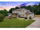 Stately two-story home with painted brick, front porch, long driveway, and professionally landscaped yard at dusk at 2015 Clipper Straits, Snellville, GA 30078