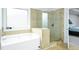 Bright bathroom featuring a glass shower and a large soaking tub beneath a window at 3869 Maiden Fern Ln, Snellville, GA 30039