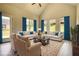 Bright and airy living room with vaulted ceiling, hardwood floors, and large windows with blue curtains at 670 Park Place Way, Social Circle, GA 30025