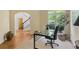 Bright office space with a modern glass desk, large windows, and hardwood floors with view to the staircase at 5355 Highland Pine Ln, Mableton, GA 30126