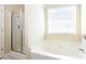 Bathroom featuring a separate glass-door shower and a soaking tub beneath a window at 4628 Mcever View Dr, Sugar Hill, GA 30518