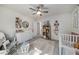 Bedroom with white crib, floral wallpaper accents, and ceiling fan above at 6070 Lively Ct, Cumming, GA 30040