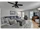 Comfortable living room features a gray sectional, ottoman, modern ceiling fan and natural light from multiple windows at 939 Flowers Xing, Lawrenceville, GA 30044