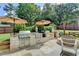 Stone outdoor kitchen has a grill, preparation area, and umbrellas for relaxing at 939 Flowers Xing, Lawrenceville, GA 30044