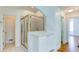 Bright bathroom featuring a glass-enclosed shower with gold trim, white cabinets, and ceramic tile flooring at 127 Grandmar Chase, Canton, GA 30115