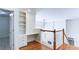 Open loft area showcasing a built-in desk with shelving, hardwood floors, and a staircase with white balusters at 127 Grandmar Chase, Canton, GA 30115