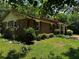 Side view of a brick home with a red roof, dark shutters, a small garden, and a green lawn at 199 Mckaskey Creek Se Rd, Cartersville, GA 30121