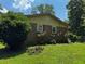 Side view of a brick and yellow home with a red roof, a small garden, and a green lawn at 199 Mckaskey Creek Se Rd, Cartersville, GA 30121