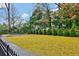 Expansive backyard with lush green lawn, mature trees, and a basketball court, offering ample space for recreation at 49 Conifer Park Ln, Atlanta, GA 30342