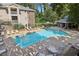 Community pool with lounge chairs and umbrellas surrounded by mature trees and an apartment building at 511 Barrington Hills Dr, Atlanta, GA 30350